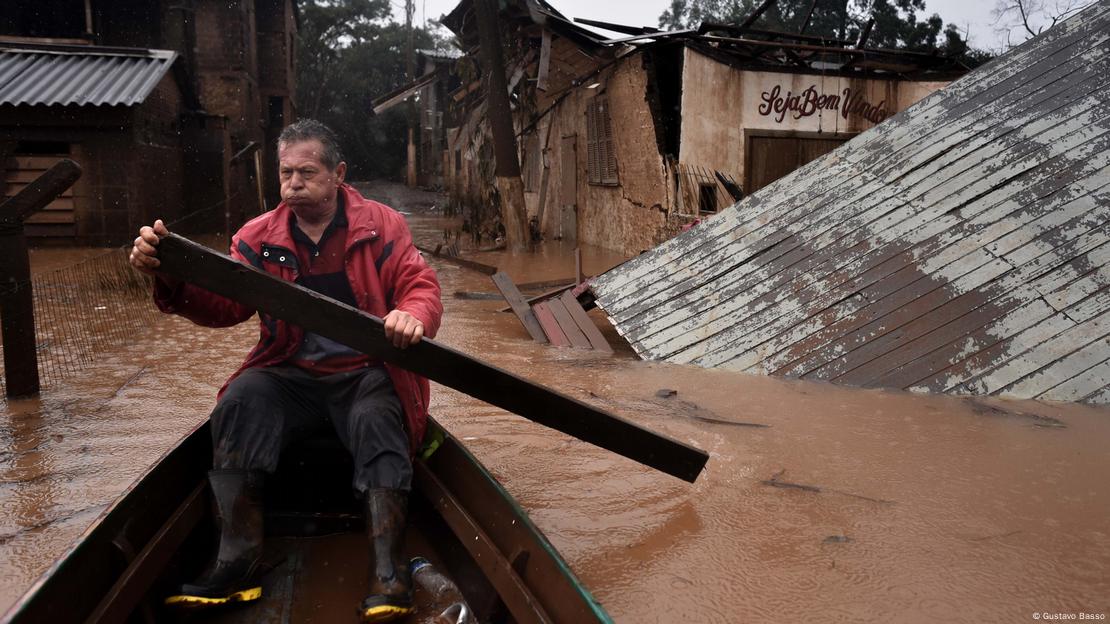 Homem em canoa usa tábua como remo improvisado durante inundação