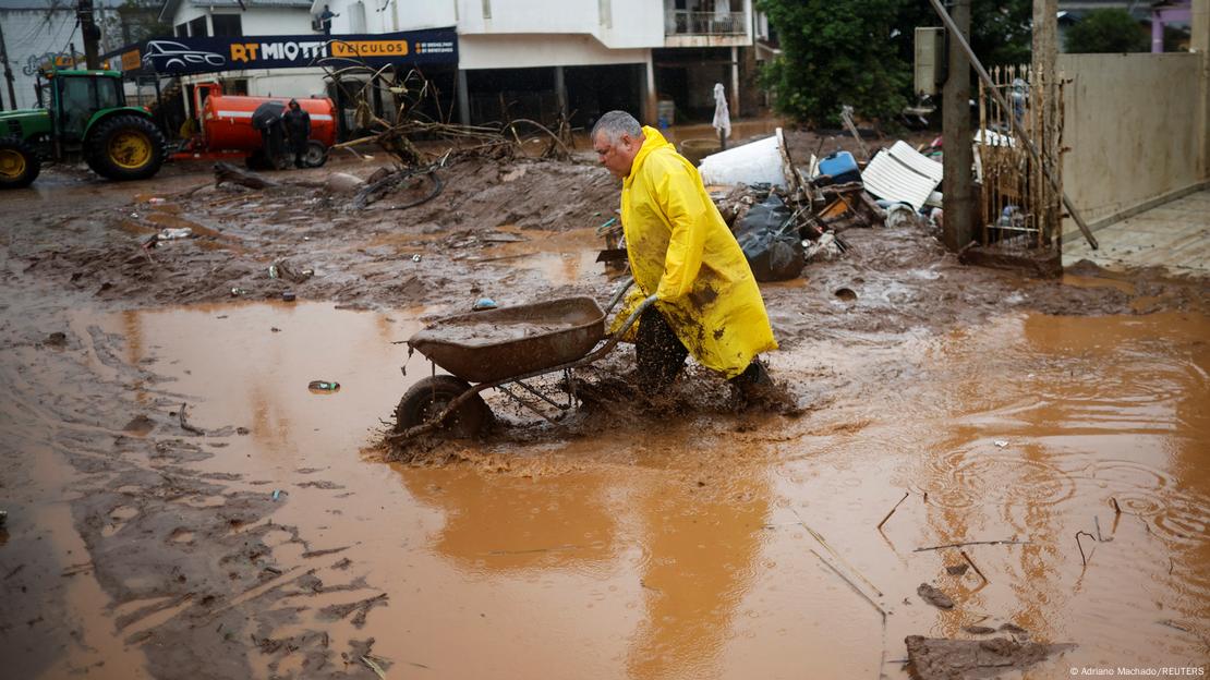 Homem com carrinho de mão caminha na lama