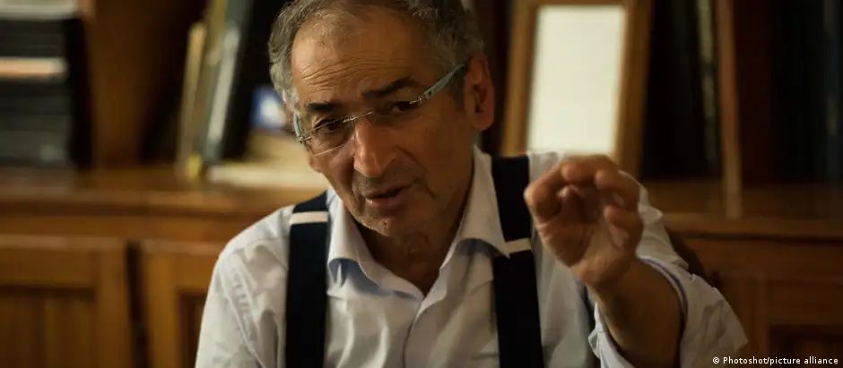 Zibakalam gestures with his left hand towards the camera during an interview in 2017