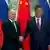 Russian President Vladimir Putin and Chinese President Xi Jinping shake hands in front of Russian and Chinese flags during a meeting in Beijing, China, May 16, 2024