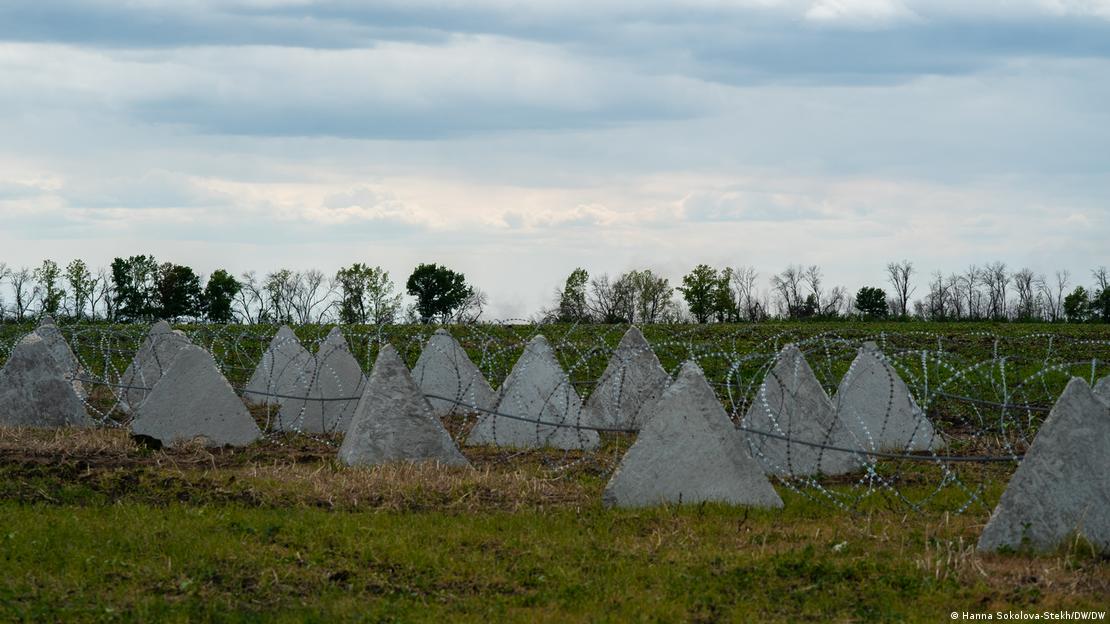 Estruturas triangulares de cimento dispostas em um campo junto com arame farpado