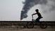 Boy cycling past fossil fuel flaring in Iraq Boy cycling past fossil fuel flaring in Iraq