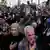 Multidão de homens erguendo cartazes com o rosto do presidente iraniano