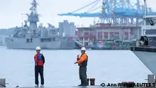 Two staff members look on as navy ships park at the port, as China announces new military drills around Taiwan, in Keelung, Taiwan May 23, 2024. REUTERS/Ann Wang
