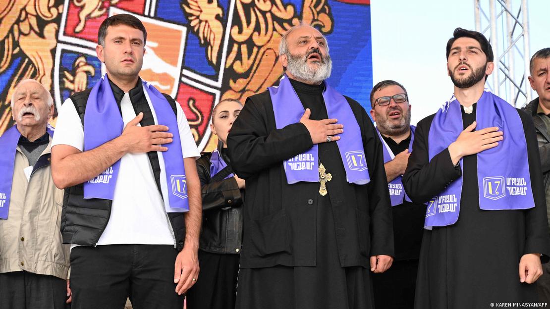 Archbishop Bagrat Galstanyan and others put their hands on their hearts during a protest rally