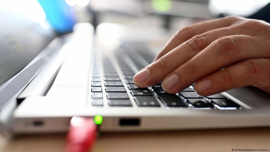 Das Bild zeigt ein im Profil zu sehendes Notebook, von rechts liegt eine Hand über der Tastatur