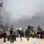 Palestinos huyen con sus pertenencias entre columnas de humo en el área de Tel al-Sultan, en Rafah, una zona azotada por los bombardeos israelíes. (Imagen de archivo: 30.05.2024)