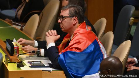Човек со очила и завиткан со српско знаме (српскиот претседател Александар Вучиќ) седи на маса во ОН и ги следи преговорите за воспоставување Ден на сеќавање на геноцидот во Сребреница