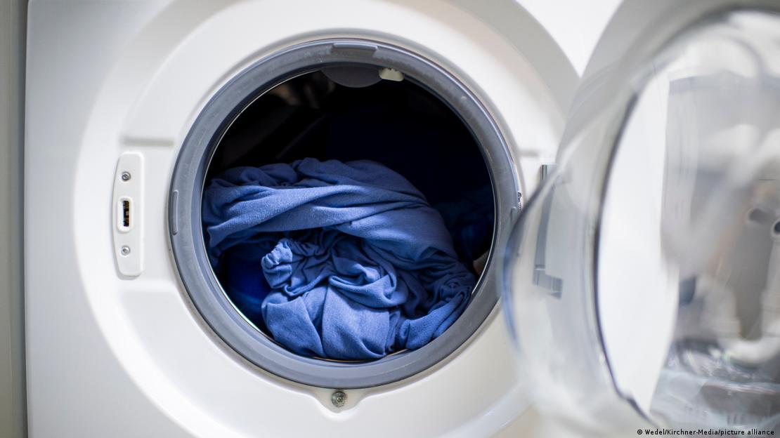Bir çamaşır makinesinin kapağı açık, içindeki çamaşır görünüyor 