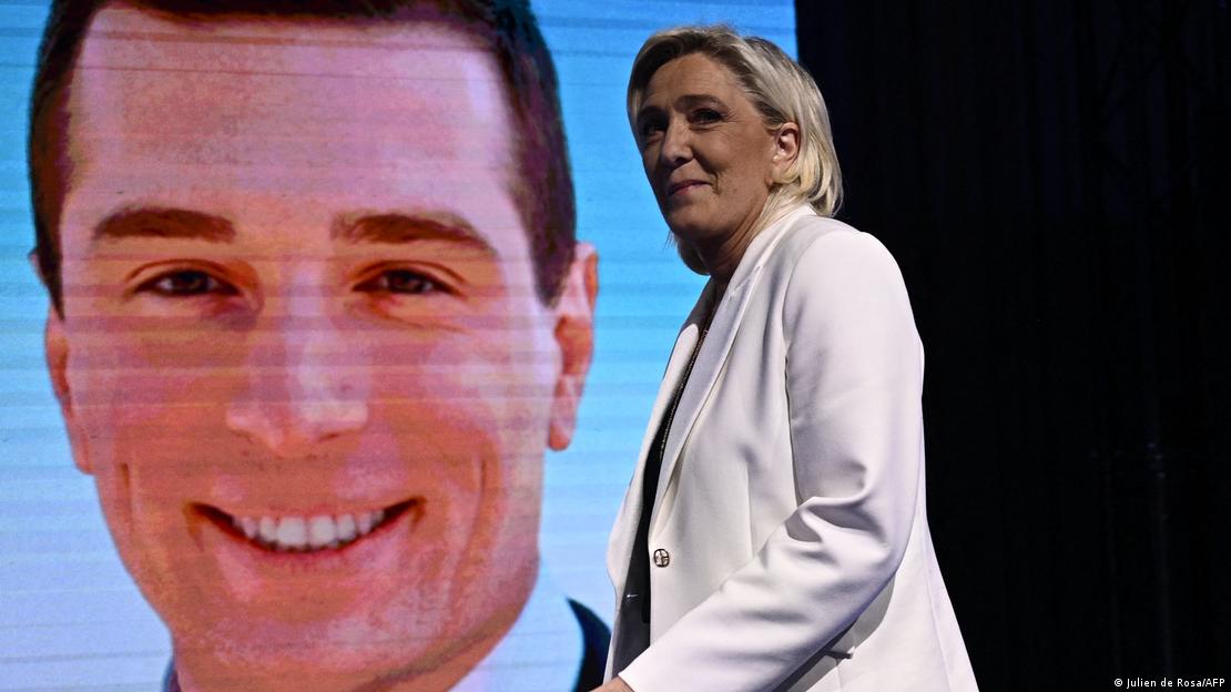 Marine de Le Pen em frente a uma projeção que mostra Jordan Bardella, seu apadrinhado político