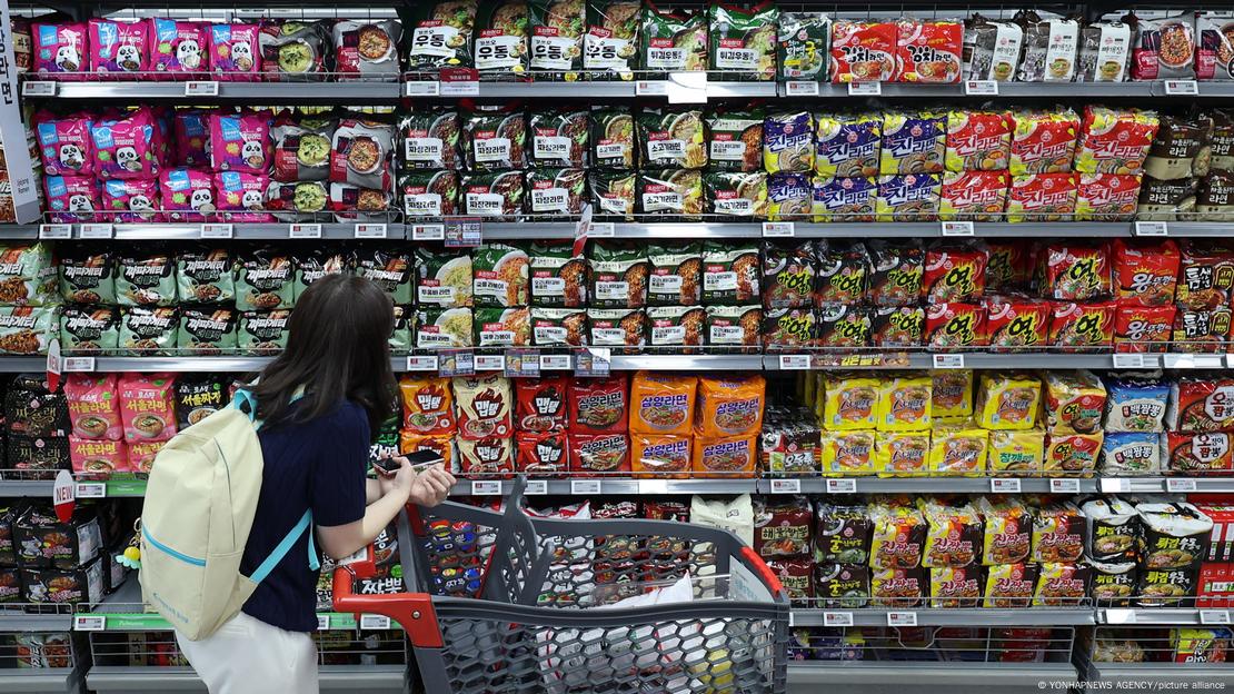 Mulher observa gôndola com produtos industrializados em supermercado