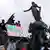 Left wing protesters climb statues in Paris to display signs in support of a new leftist alliance