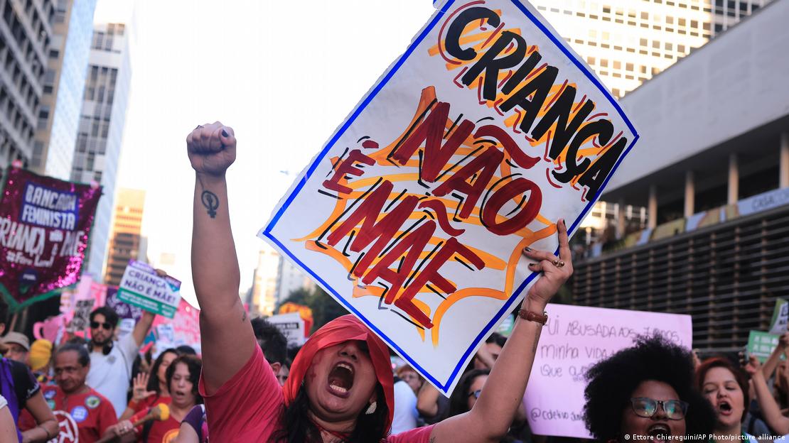 Brazilian woman at protest holding a sign reading "Criança Não é Mãe" ("a child is not a mother") on June 15, 2024.