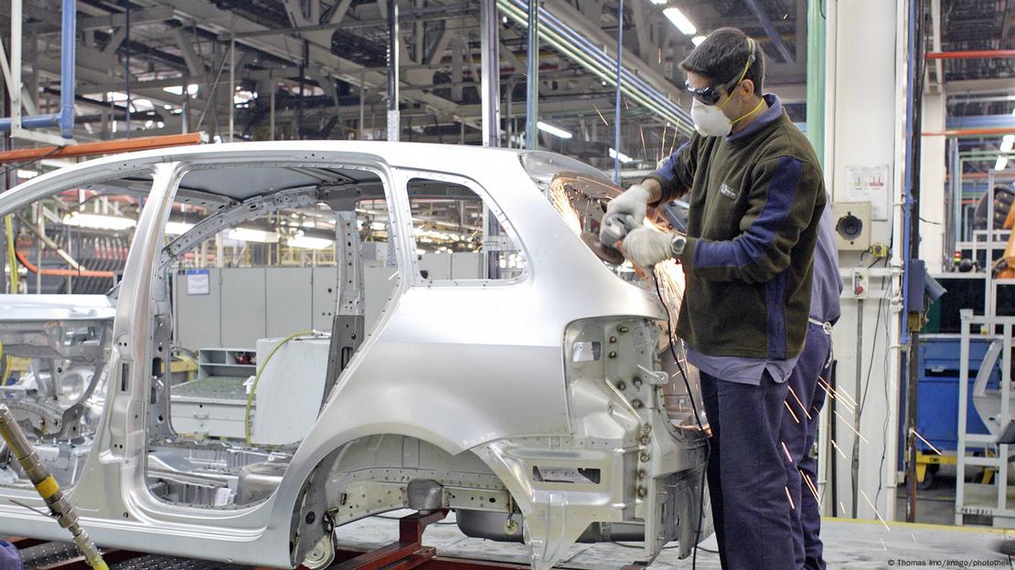 Un hombre trabaja en el montaje de un auto de VW en Argentina.