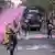 Protesters run in front of a police truck spraying dyed water from its water cannon