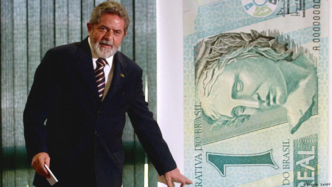 Lula ao lado de uma nota grande de 1 real