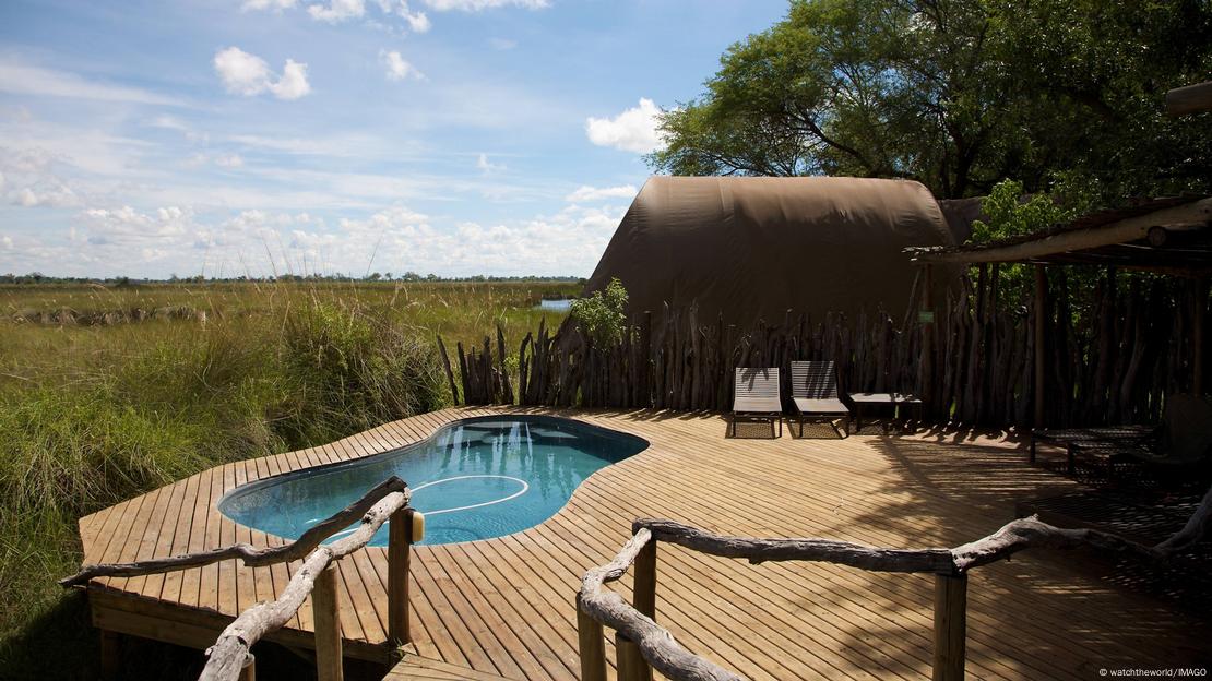 The view of a rustic deck and pool overlooking what appear to be an empty grassland