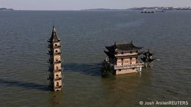 Vista aérea desde un dron de un templo en una isla del lago, del que la torre y una pagoda emergen directamente del agua.