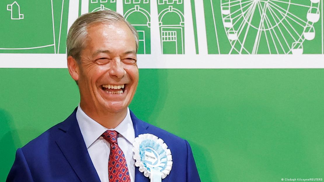 Wahlkämpfer Nigel Farage steht lachend vor einer grünen Wand mit weißen Zeichnungen