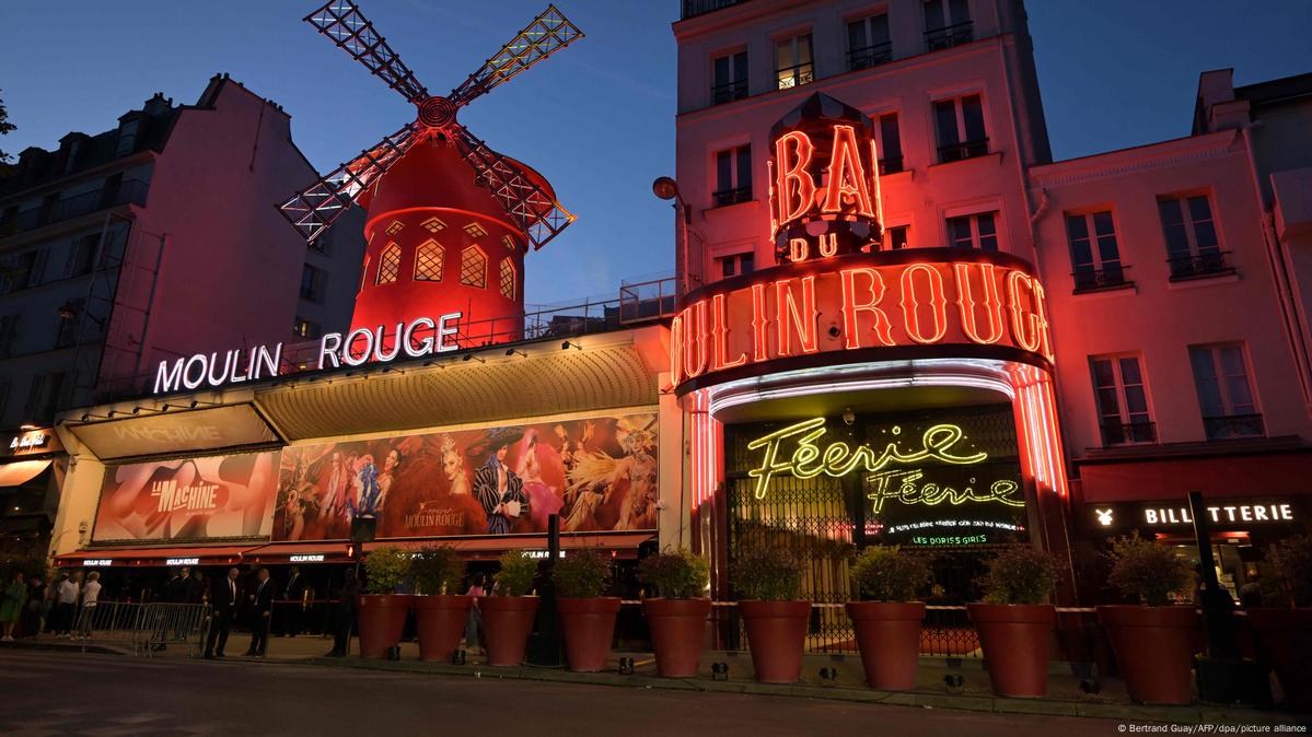 Paris, Moulin Rouge cabaret, illuminated red windmill sign, at night, with a marquee below.