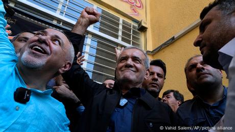 Mehrere Männer stehen jubelnd um Masoud Pezeshkian herum, der Kandidat für die Präsidentschaftswahl im Iran ist.