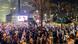 Viele Demonstranten mit israelischen Fahnen stehen Abends auf einem Platz in Tel Aviv Viele Demonstranten mit israelischen Fahnen stehen Abends auf einem Platz in Tel Aviv