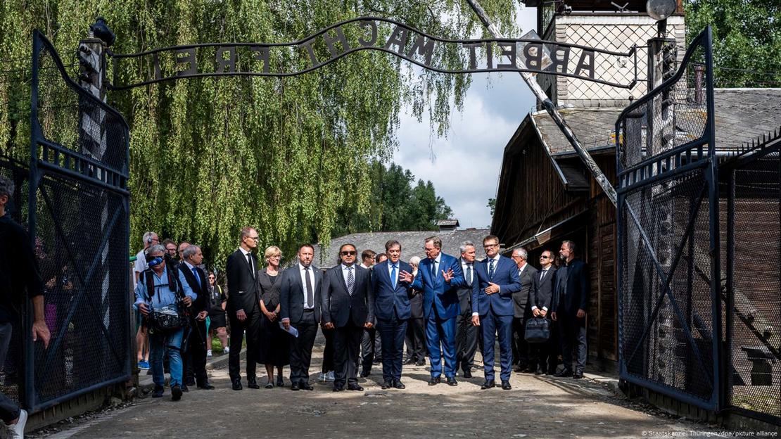 Eine Gruppe von Menschen geht durch ein Eingangstor (das Tor in Auschwitz)