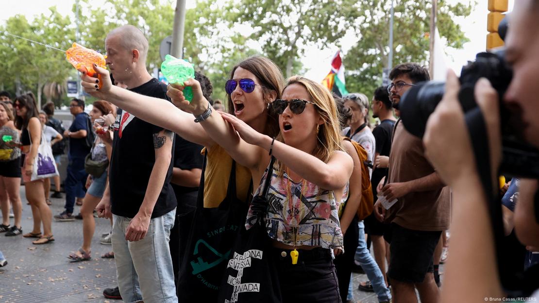 Foto de personas que protestan contra turistas con pistolas de agua en Barcelona.