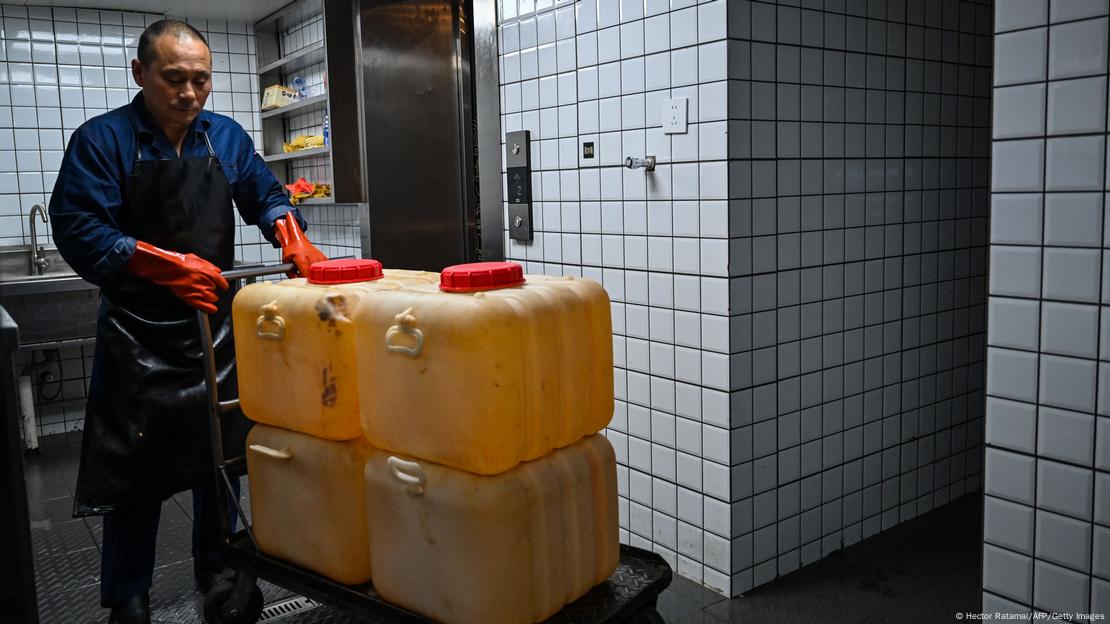 Esta fotografía, tomada el 21 de octubre de 2023, muestra a un trabajador transportando aceite usado para reciclarlo de un restaurante de hot pot en Chengdu, provincia de Sichuan, en el suroeste de China.