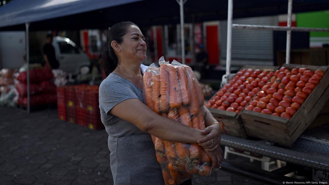 Foto simbólica de una persona que lleva zanahorias de un agro-mercado gubernamental en El Salvador.