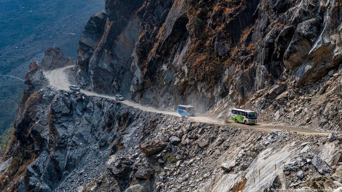 Buses pictured traveling along a mountain pass in Nepal in 2023