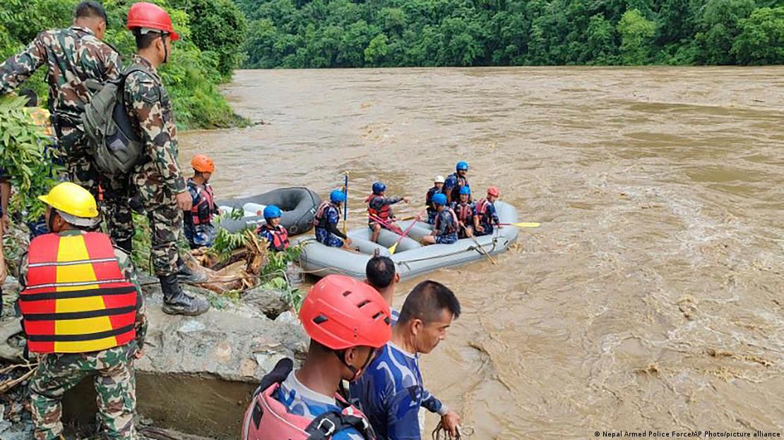 Rescuers on land and in a inflatable boat look for the survivors after two buses were swept by a landslide off the highway and into a swollen river near Simaltal