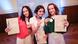 Three teenaged girls hold up gold medals that they are wearing around their necks and certificates of German language knowledge Three teenaged girls hold up gold medals that they are wearing around their necks and certificates of German language knowledge