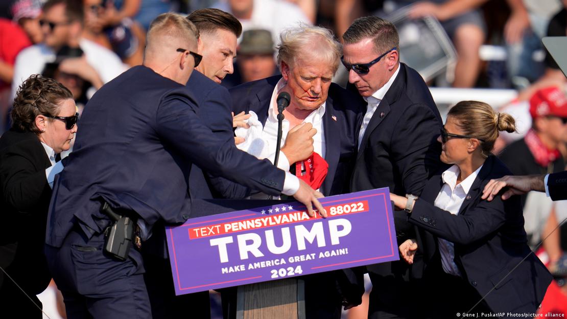 Trump é amparado e escoltado às pressas por agentes do Serviço Secreto após ser baleado de raspão na orelha; foto de 13 de julho de 2024