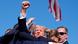 Donald Trump raising a fist surrounded by security agents soon after an apparent shooting at a rally in Butler, Pennsylvania, on July 13, 2024. 