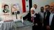 A woman casts her ballot at a polling station during parliamentary elections, in Damascus, Syria, with photos of Bashar Assad in the background, including one with the text "We love you." A woman casts her ballot at a polling station during parliamentary elections, in Damascus, Syria, with photos of Bashar Assad in the background, including one with the text "We love you."