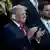 Former US President Donald Trump with a patch on his ear following a shooting applauds while standing next to JD Vance