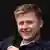 Sebastian Hotz, young man holding a microphone while smiling and looking to the side