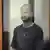 Evan Gershkovich é um homem branco de 32 anos; ele veste uma camiseta cinza, tem o cabelo raspado e está dentro de uma sala de vidro 