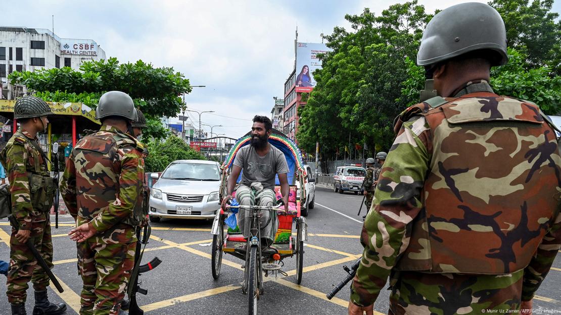 Bangladeshi soldiers guard road as man on bike rides by