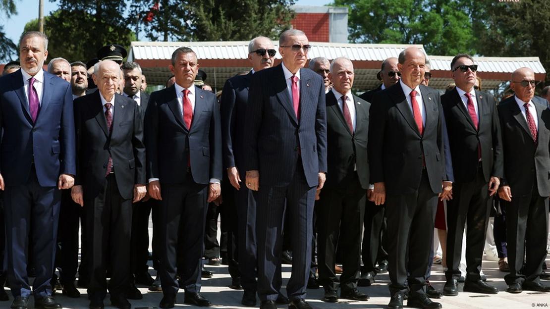 Türkiye'nin düzenlediği Kıbrıs harekâtının 50'inci yıl dönümünde Lefkoşa'da düzenlenen törenden bir kare. En ön sırada Recep Tayyip Erdoğan ve Ersin Tatar ayakta duruyor. Arkalarındaki sırada ise Hakan Fidan, Devlet Bahçeli ve Özgür Özel dâhil çok sayıda isim var.