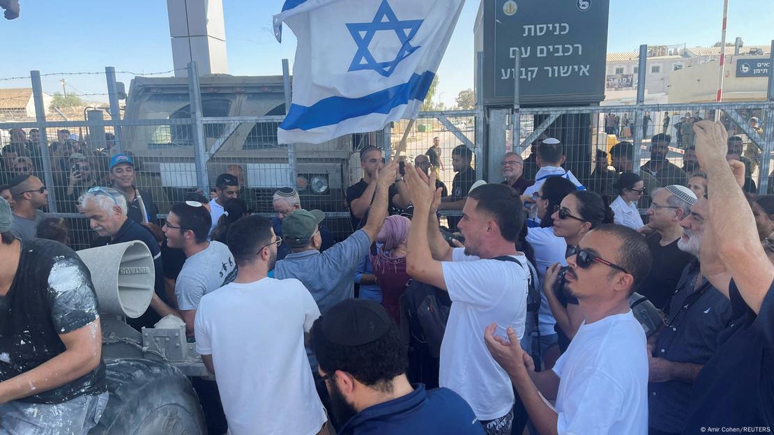 Ultradireitistas protestam em frente a cerca da base militar de Israel. Bandeira israelenses aparece em meio à multidão Ultradireitistas protestam em frente a cerca da base militar de Israel. Bandeira israelenses aparece em meio à multidão