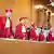 Judges wearing a red robes and a red hat stand in a row.