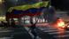Eine Demonstrantin schwenkt eine große venezolanische Flagge im Dunkeln auf der Straße, ein Feuer brennt auf der Fahrbahn Eine Demonstrantin schwenkt eine große venezolanische Flagge im Dunkeln auf der Straße, ein Feuer brennt auf der Fahrbahn