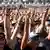 A large crowd stand and hjold up there arm and form a devil horms salute