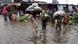 People carry vegetables through a flooded road caused by heavy monsoon rainfall in Lahore, Pakistan, Thursday, August 1, 2024 People carry vegetables through a flooded road caused by heavy monsoon rainfall in Lahore, Pakistan, Thursday, August 1, 2024