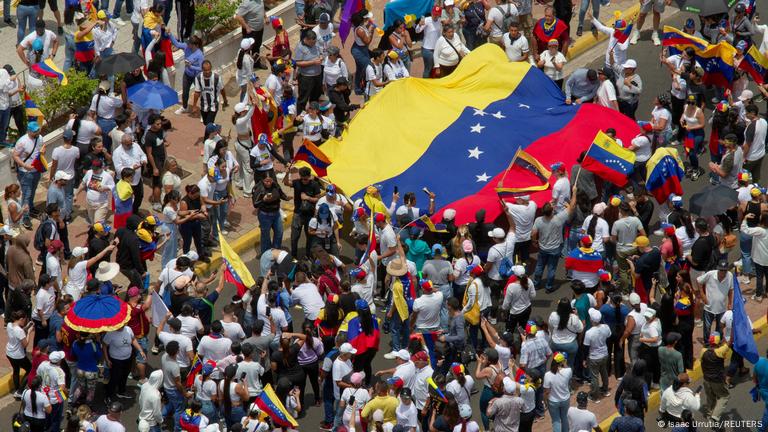 Protestas de la oposición contra la reelección de Maduro, en Maracaibo: la gente porta una inmensa bandera de Venezuela.