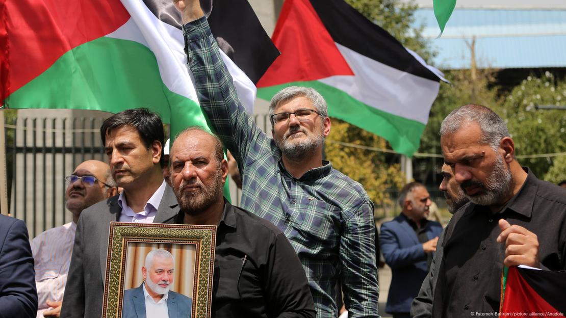 Marcha durante el duelo en Teherán por el asesinato de Ismail Haniyeh: un hombre lleva su retrato en medio de banderas palestinas e iraníes.