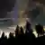 La vía láctea en el cielo nocturno de Baviera, en Alemania. En el borde inferior de la imagen: silueta de copas de pinos.