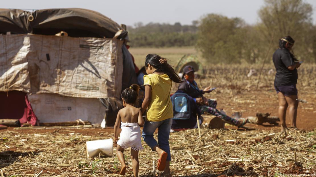 Duas crianças indígenas andam no acampamento 